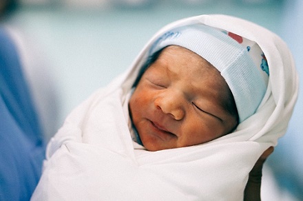 Newborn baby swaddled and wearing hat