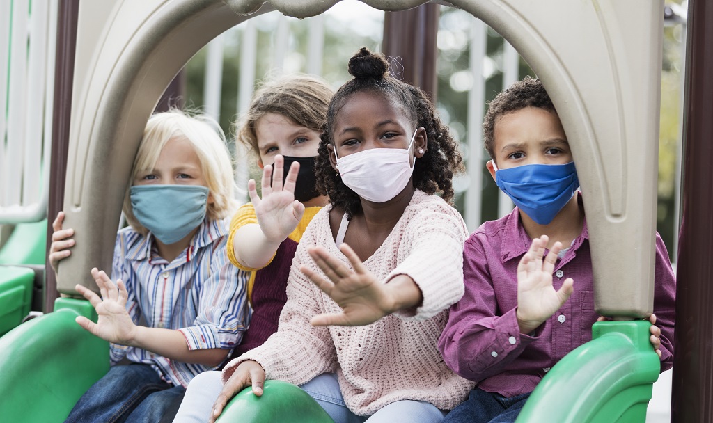 Children on playground slide wearing masks