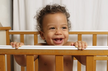 Baby in crib, pulling up on side, smiling